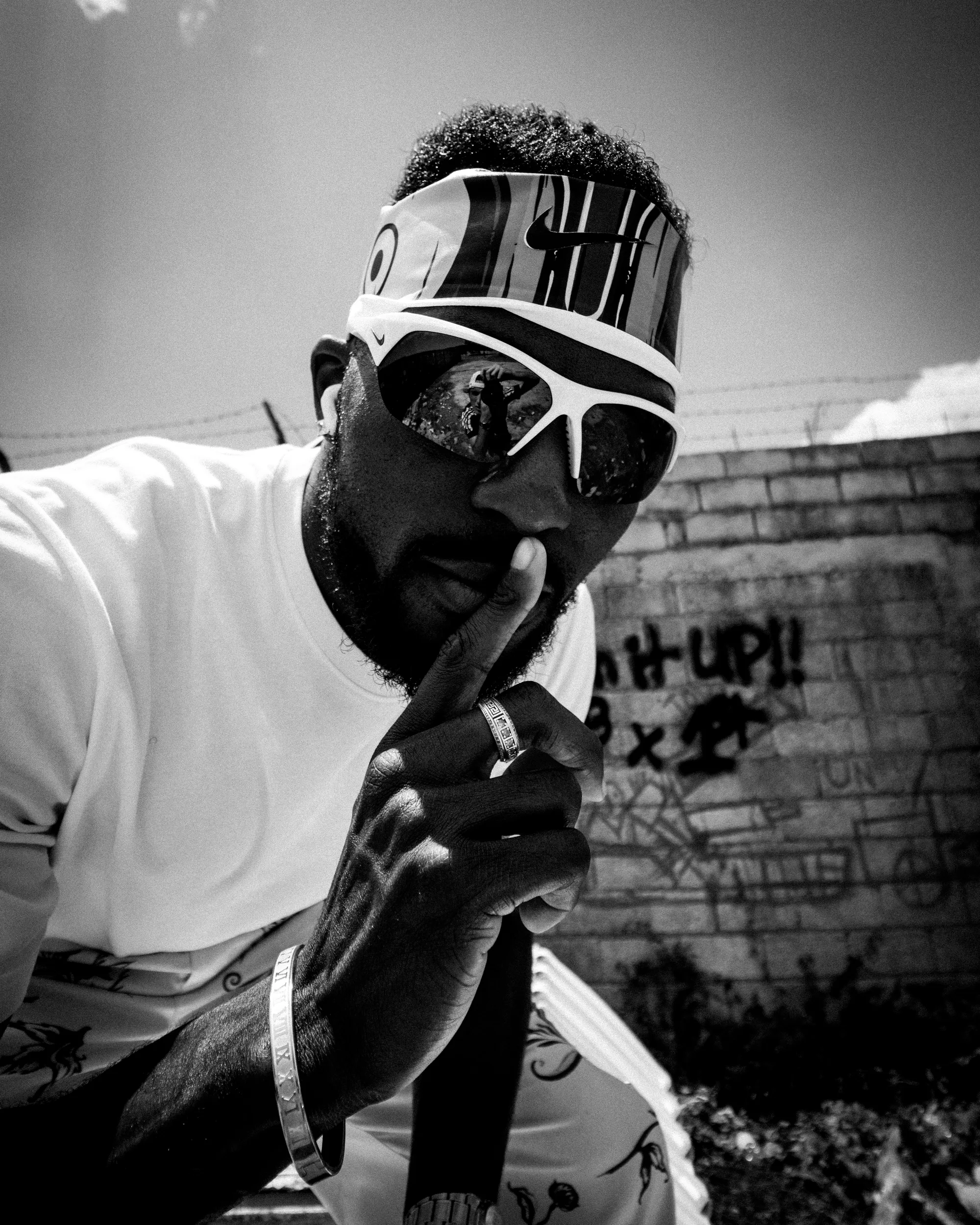 Kenny Bednarek in sunglasses against a weathered wall